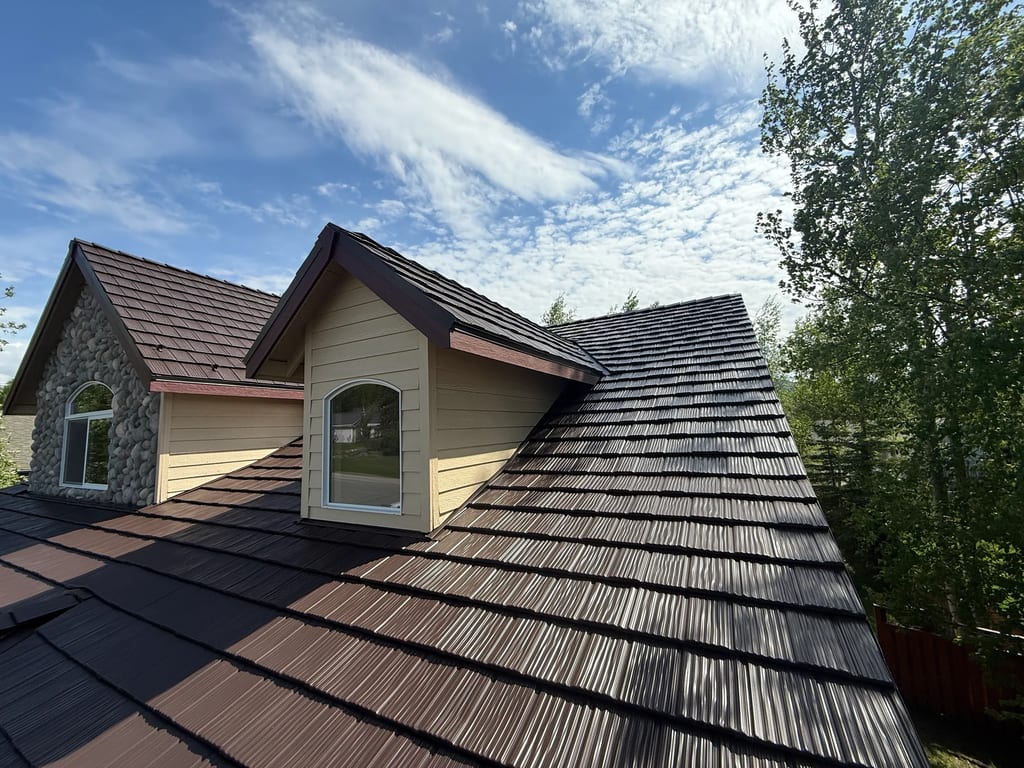 A modern single-family home with a dark metal roof and beige siding.