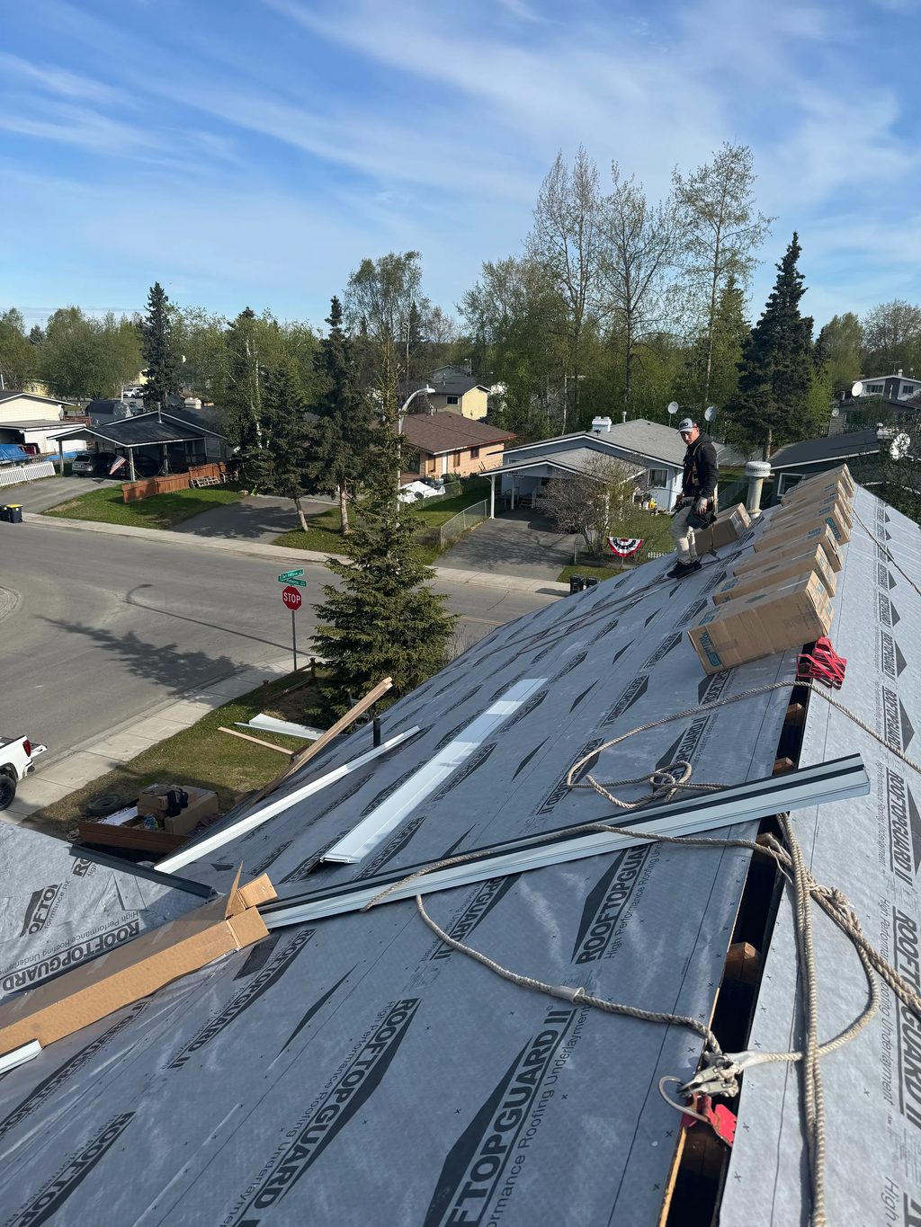 A metal roof under construction on a modern single-family home in an urban or suburban area.
