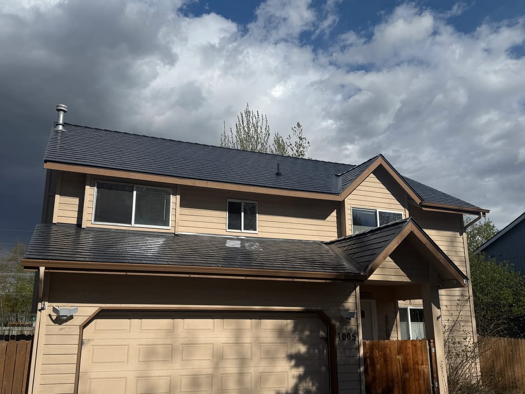 A modern-style house with a grey metal roof and beige siding