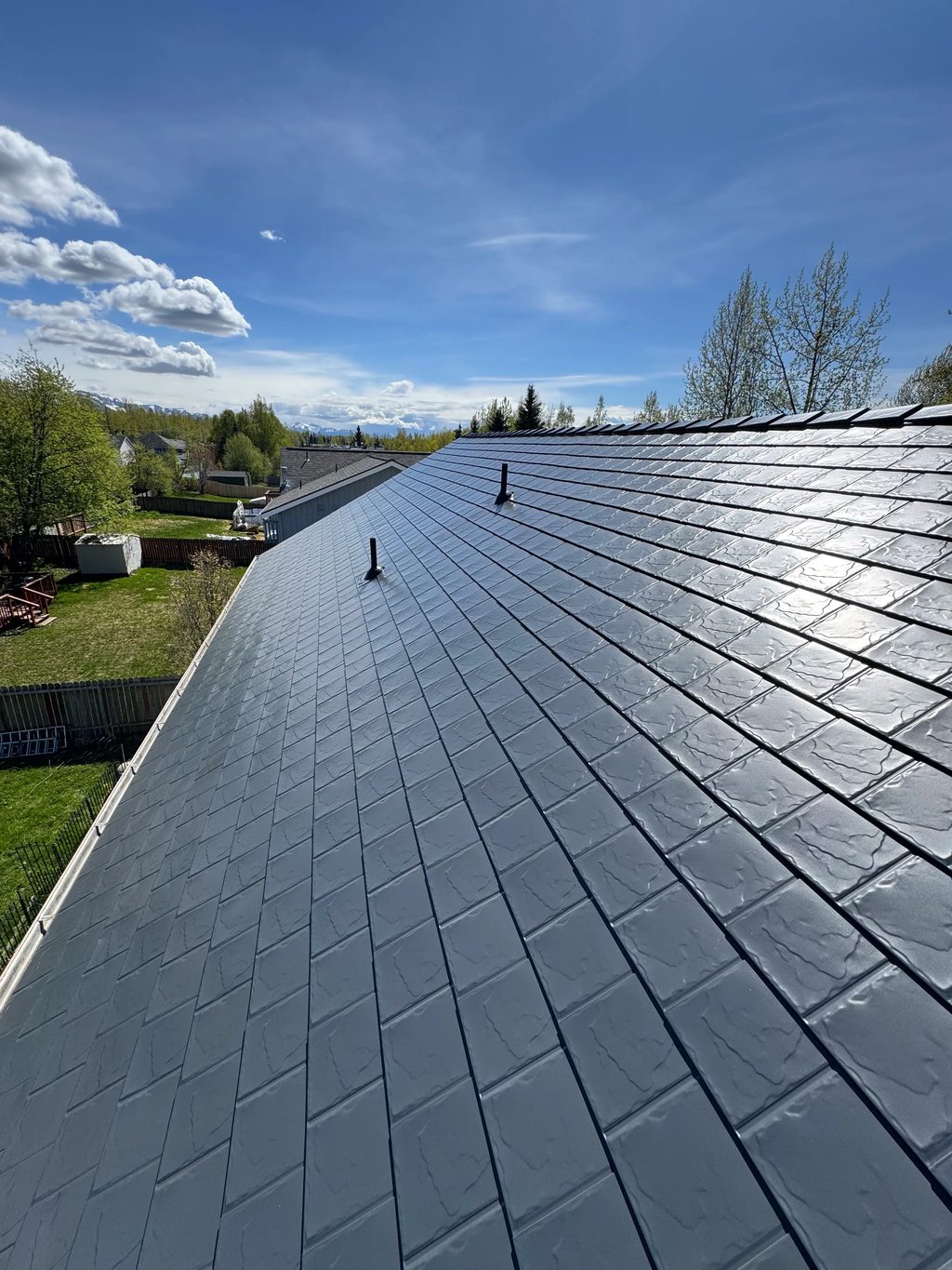 A modern metal roof in a suburban setting with lush greenery.