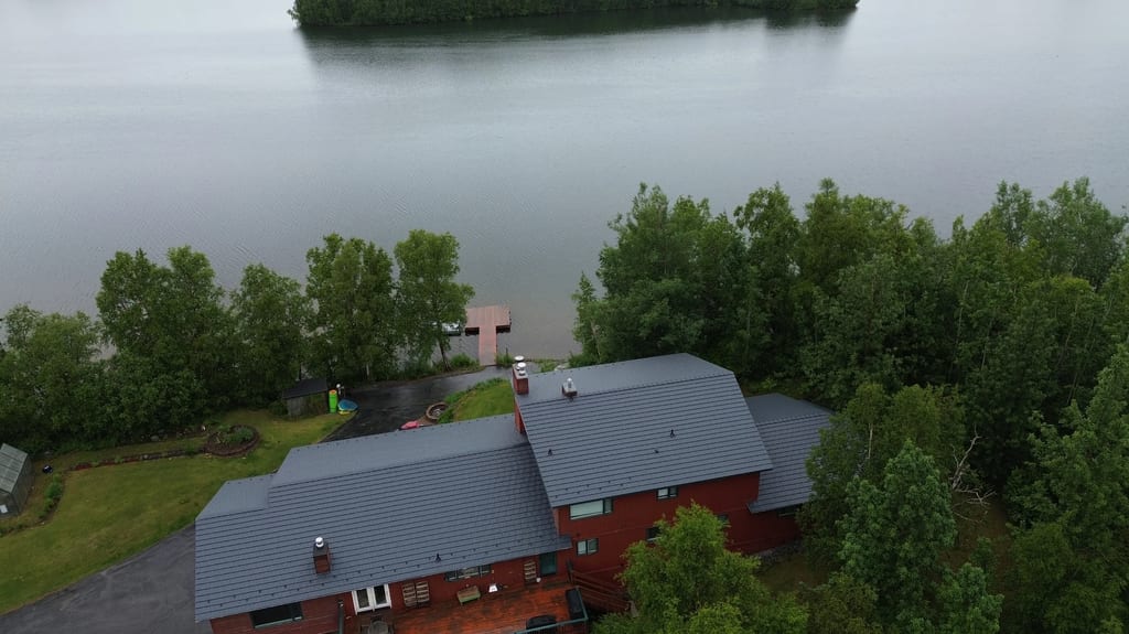Aerial view of a red brick house with a grey metal roof