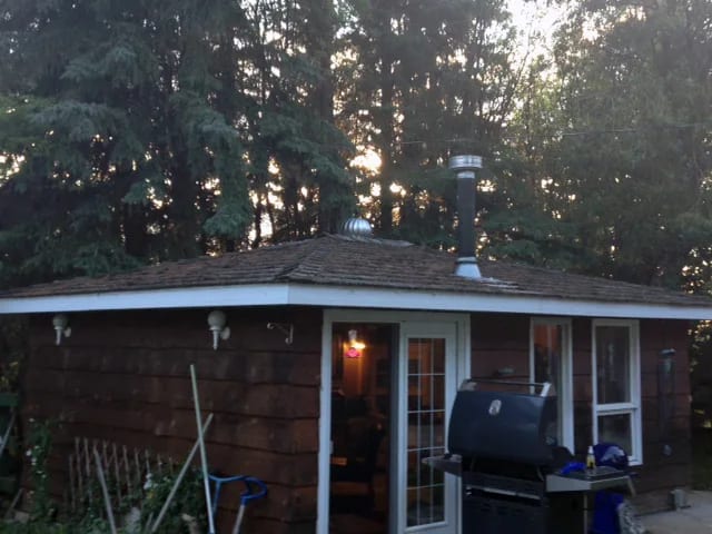 Black Interlock Slate aluminum roof on a brown ranch home with chimney among tall trees, Whitecourt, Alberta