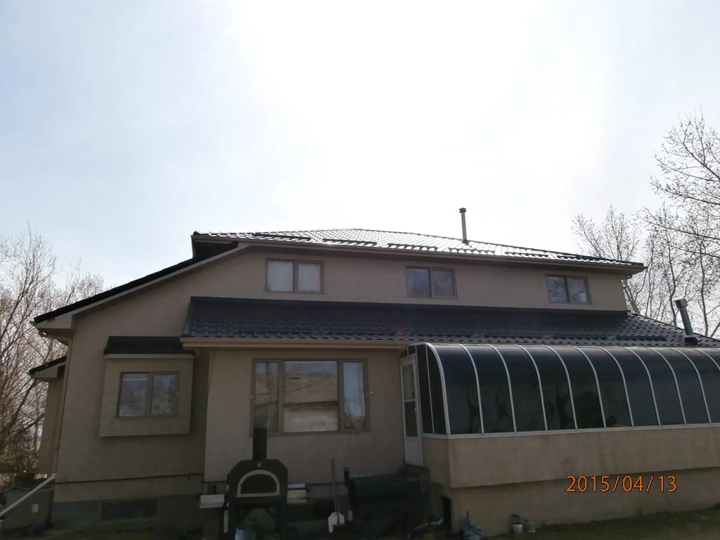 Black Interlock Tile aluminum roof on a tan single-storey home with a metal roof in rural Alberta, Redcliff, Alberta