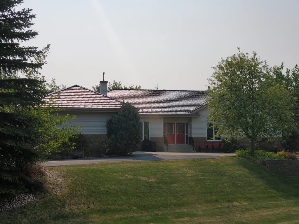 Weathered Interlock Shake aluminum roof on a white ranch home with a red door among tall trees, Sherwood Park, Alberta