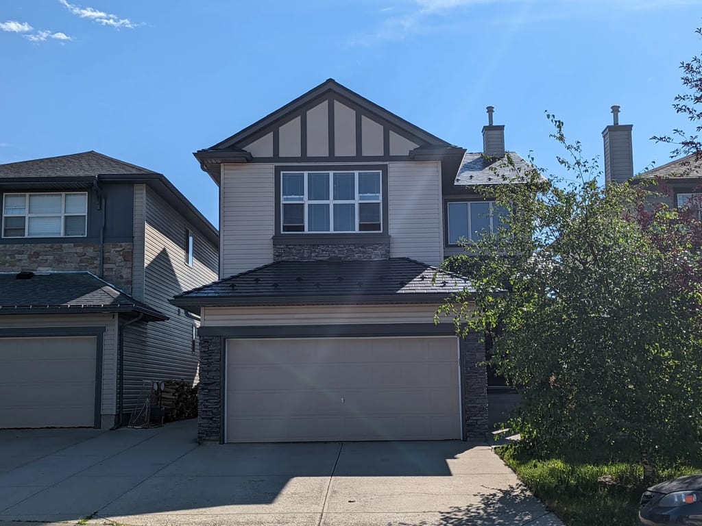 Black Interlock Slate aluminum roof on a two-storey home with dormers and metal roof among tall, Calgary, Alberta