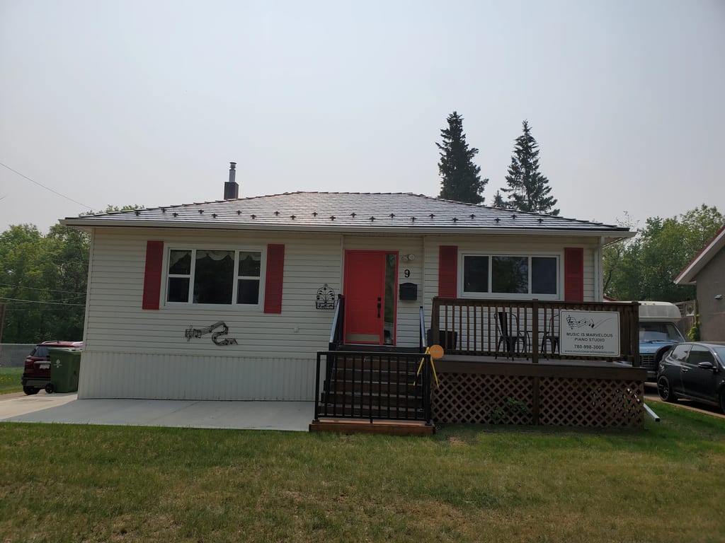 Black Interlock Slate aluminum roof on a white single-storey ranch home with dormers among tall, Fort Saskatchewan, Alberta