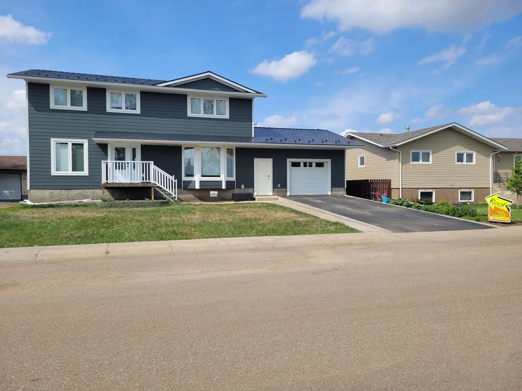 Black Interlock Slate aluminum roof on a dark two-storey home with metal roof in a rural setting, Oyen, Alberta