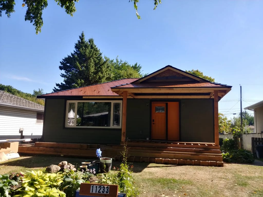 Copper Penny Interlock Slate aluminum roof on a brown home with a metal roof among trees, Edmonton, Alberta