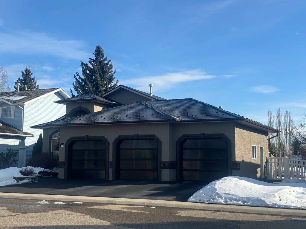 Black Interlock Slate aluminum roof on a tan home with a dark metal roof and attached garage in a, Red Deer, Alberta