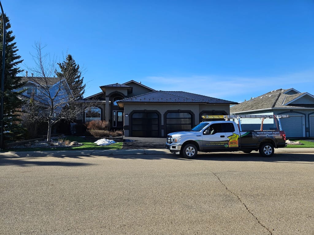 Black Interlock Slate aluminum roof being installed on a single-family home with a grey roof among urban buildings, Red Deer, Alberta