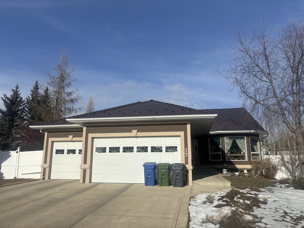 Front elevation of a single-storey ranch home in Red Deer AB featuring Interlock Colonial Brown aluminum slate metal roofing on a multi-hip complex roof.