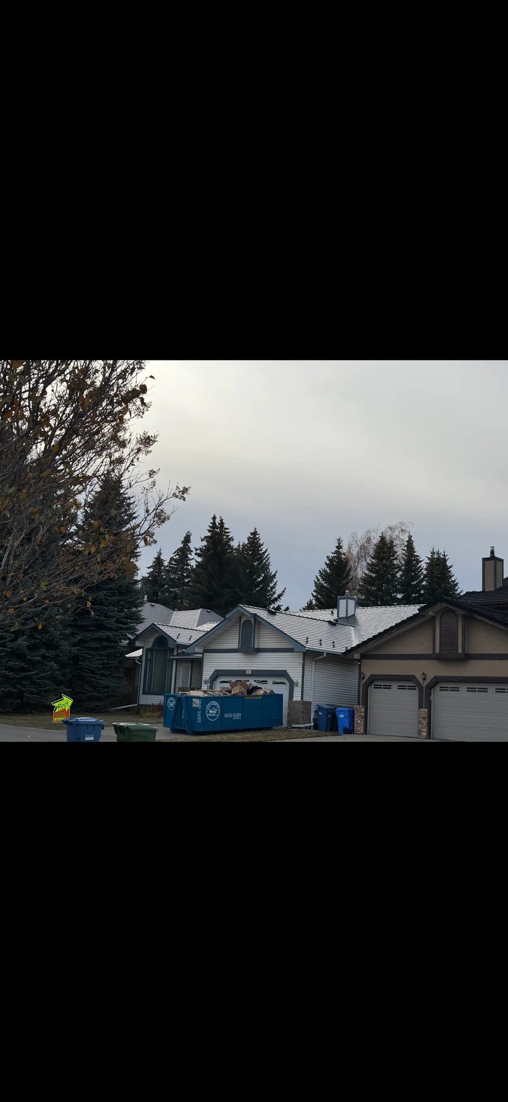 Musket Grey Interlock Slate aluminum roof being installed on a two-storey house with a metal roof under construction in, Calgary, Alberta