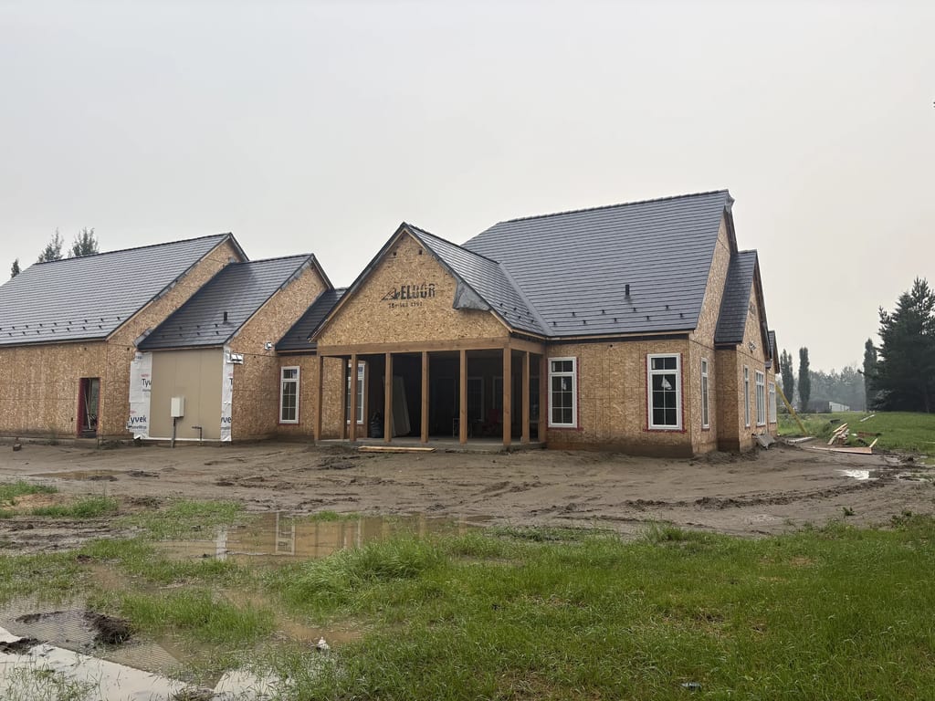 Black Interlock Slate aluminum roof being installed on a single-storey home with a metal roof under construction, Grande Prairie, Alberta