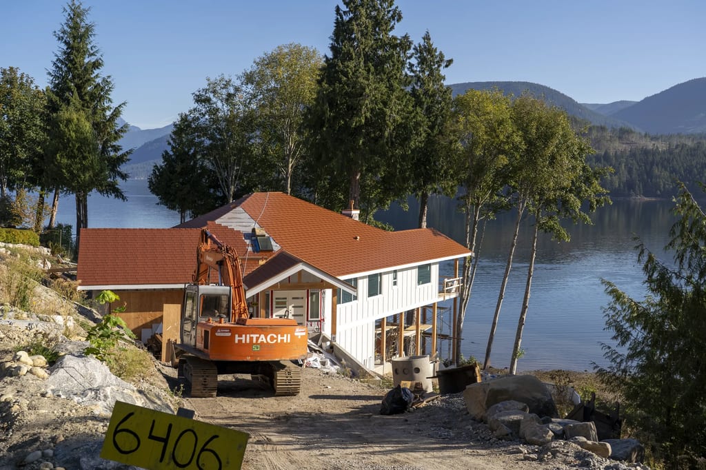 Copper Penny Interlock Slate aluminum roof being installed on a white two-storey home with dormers on a waterfront, Sechelt, British Columbia