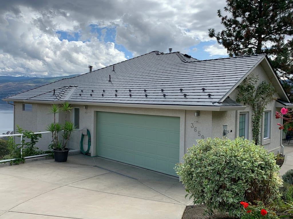 Deep Charcoal Interlock Slate aluminum roof on a modern home in the mountains with a large deck and trees, West Kelowna, British Columbia