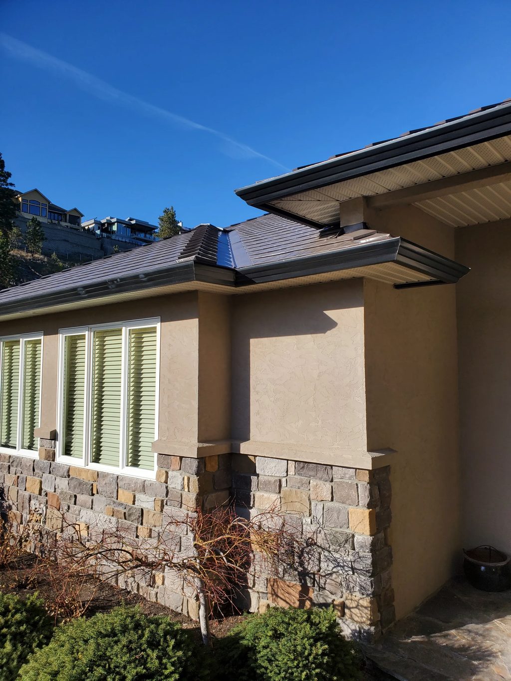 Tudor Brown Interlock Cedar Shingle aluminum roof on a Tudor-style home with stone walls in a mountain setting, West Kelowna, British Columbia