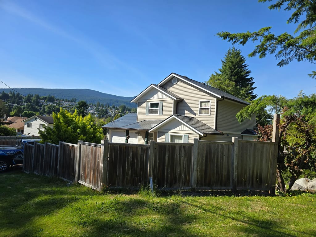 Deep Charcoal Interlock Slate aluminum roof on a two-storey home with a metal roof among tall trees in the, Gibsons, British Columbia