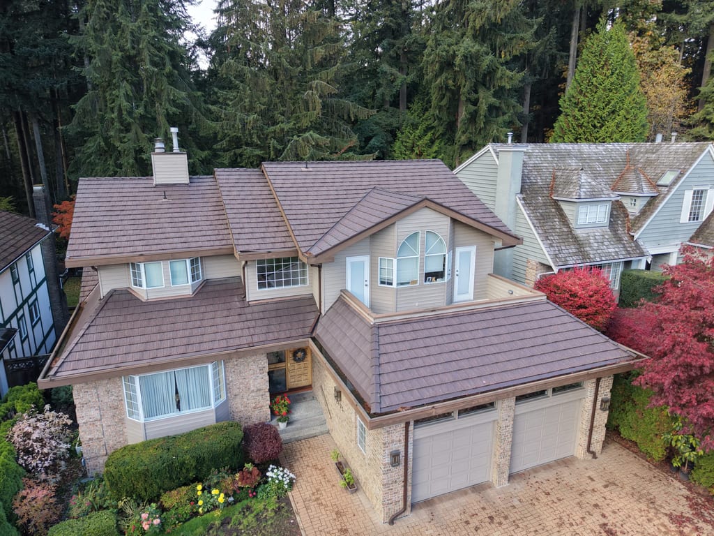 Colonial Brown Interlock Shake aluminum roof on a tan colonial home with dormers and garage amidst tall, North Vancouver, British Columbia