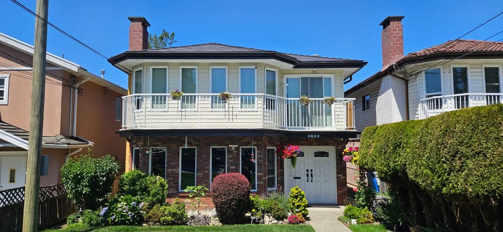 Black Interlock Slate aluminum roof on a two-storey home with brick and white siding in a forest, Burnaby, British Columbia