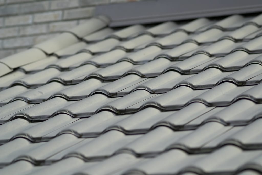 Before: a metal roof with broken tiles on the home, Surrey, British Columbia, ahead of a Black Interlock Slate aluminum roof