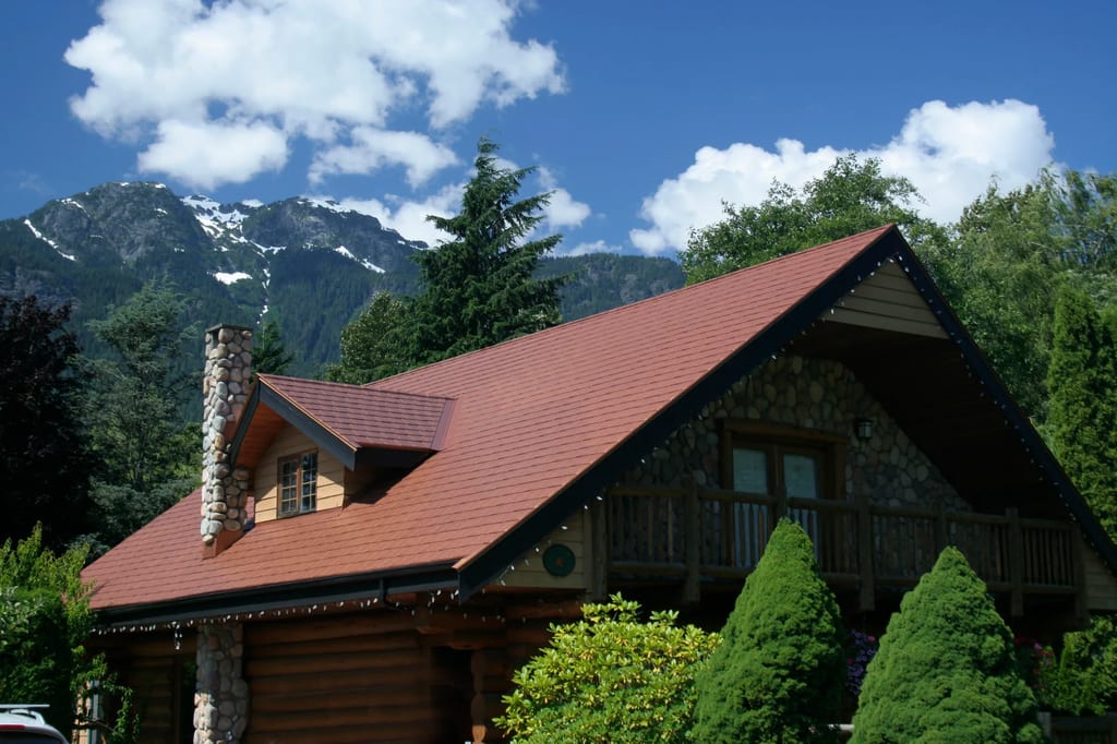 Aged Copper Interlock Slate aluminum roof on a brown chalet with a copper roof in a forested mountain, Brackendale, British Columbia