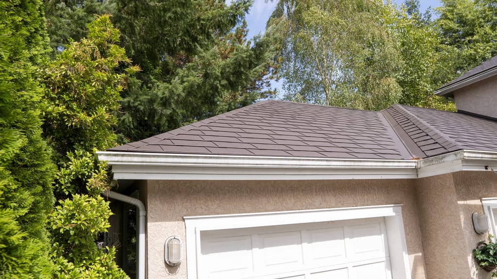 Tudor Brown Interlock Slate aluminum roof on a tan Tudor home with Interlock detail among forested, Surrey, British Columbia