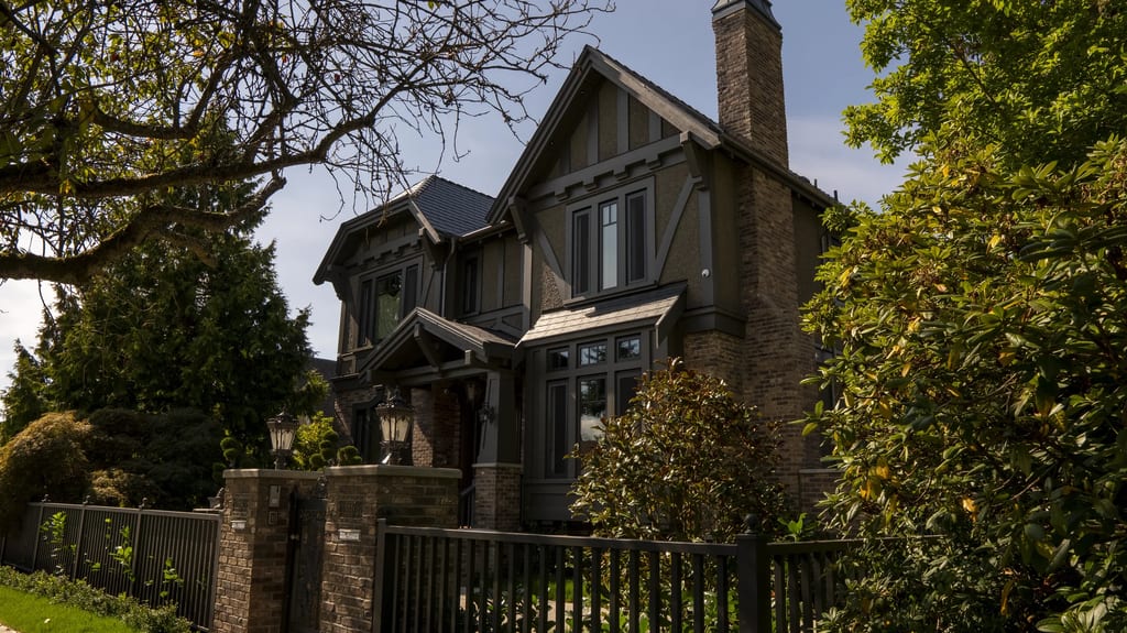 Deep Charcoal Interlock Slate aluminum roof on a brown two-storey craftsman home with dormers among tall, Vancouver, British Columbia