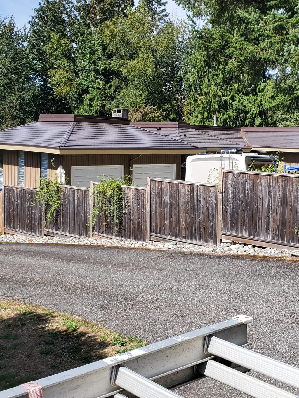 Tudor Brown Interlock Cedar Shingle aluminum roof on a brown one-storey home with a metal roof in a wooded area, Mission, British Columbia