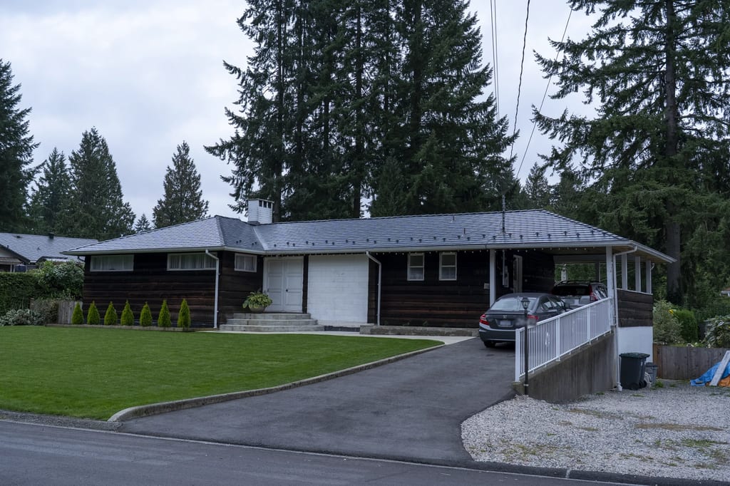 Deep Charcoal Interlock Slate aluminum roof on a brown ranch-style home with a metal roof among tall, North Vancouver, British Columbia
