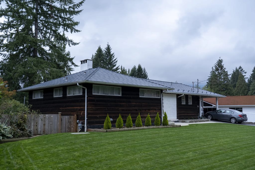 Deep Charcoal Interlock Slate aluminum roof on a dark house with a metal roof in a forested suburban, North Vancouver, British Columbia