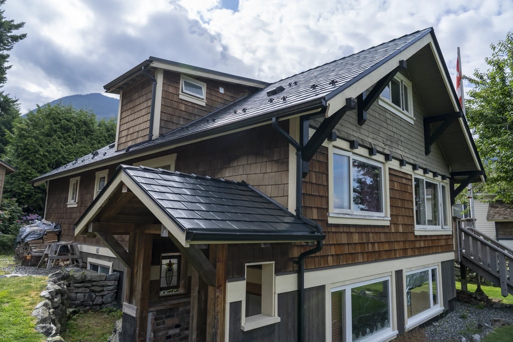 Black Interlock Slate aluminum roof on a brown chalet-style home with a metal roof in a forested, Britannia Beach, British Columbia