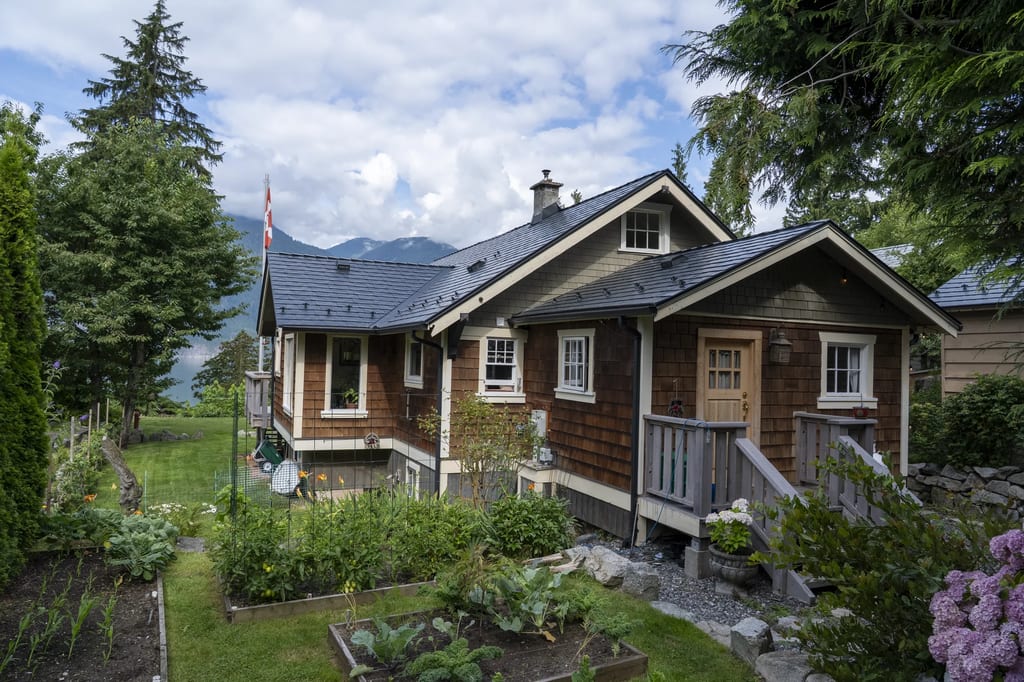 Black Interlock Slate aluminum roof on a brown cottage with a dark metal roof in a lush green, Britannia Beach, British Columbia