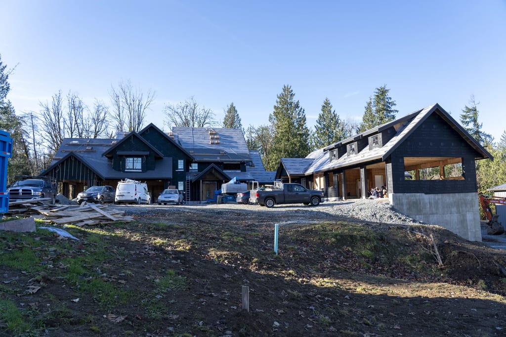 Musket Grey Interlock Slate aluminum roof being installed on a two-storey home with a black roof under construction in a, Abbotsford, British Columbia