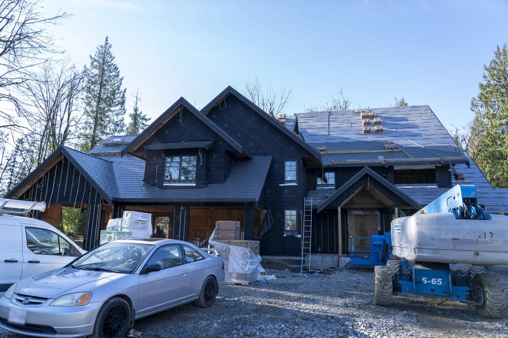 Musket Grey Interlock Slate aluminum roof being installed on a two-storey home under construction in the woods, Abbotsford, British Columbia