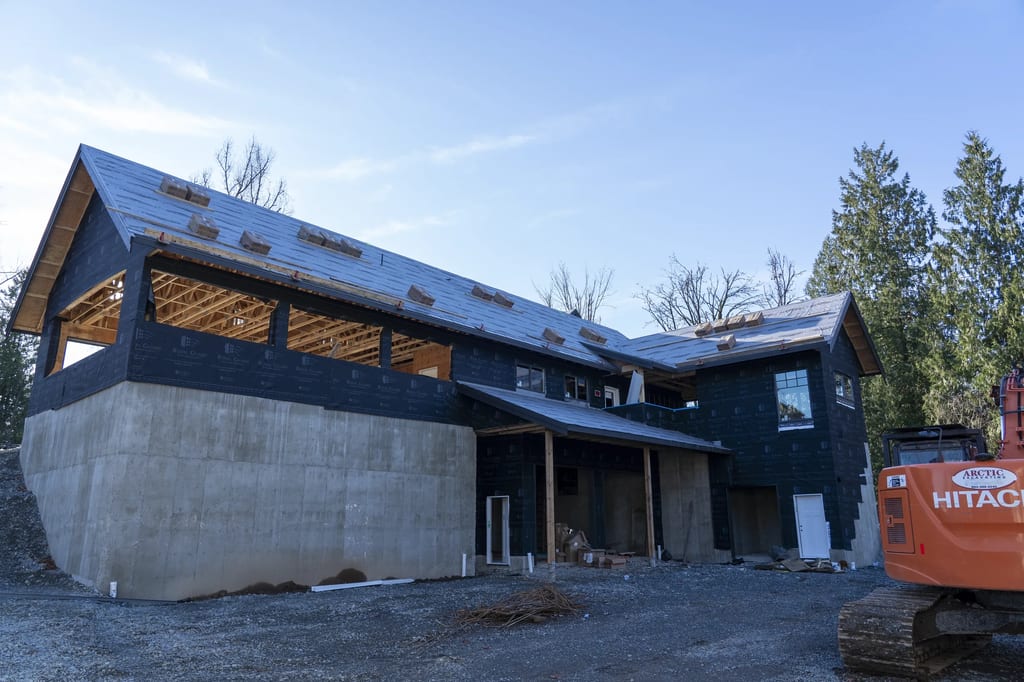 Musket Grey Interlock Slate aluminum roof being installed on a Musket Grey metal roof on a two-storey home among tall, Abbotsford, British Columbia
