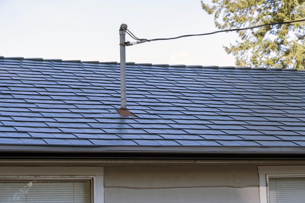 Deep Charcoal Interlock Slate aluminum roof on a beige single-family home with a metal roof in a forested, Mission, British Columbia