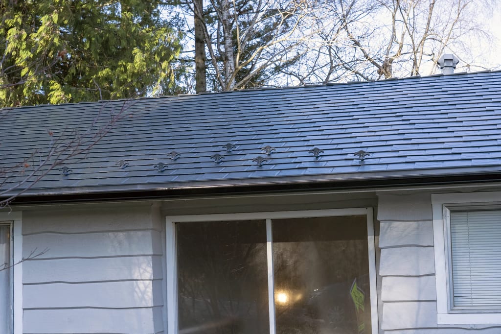 Deep Charcoal Interlock Slate aluminum roof on a white single-storey home with a gable in a forested area, Mission, British Columbia