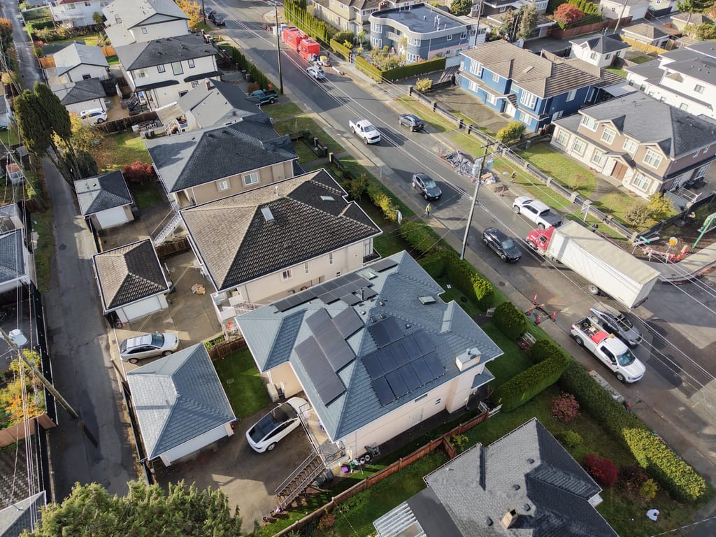 Deep Charcoal Interlock Slate aluminum roof on a tan single-family home with dormers in an urban setting, Burnaby, British Columbia