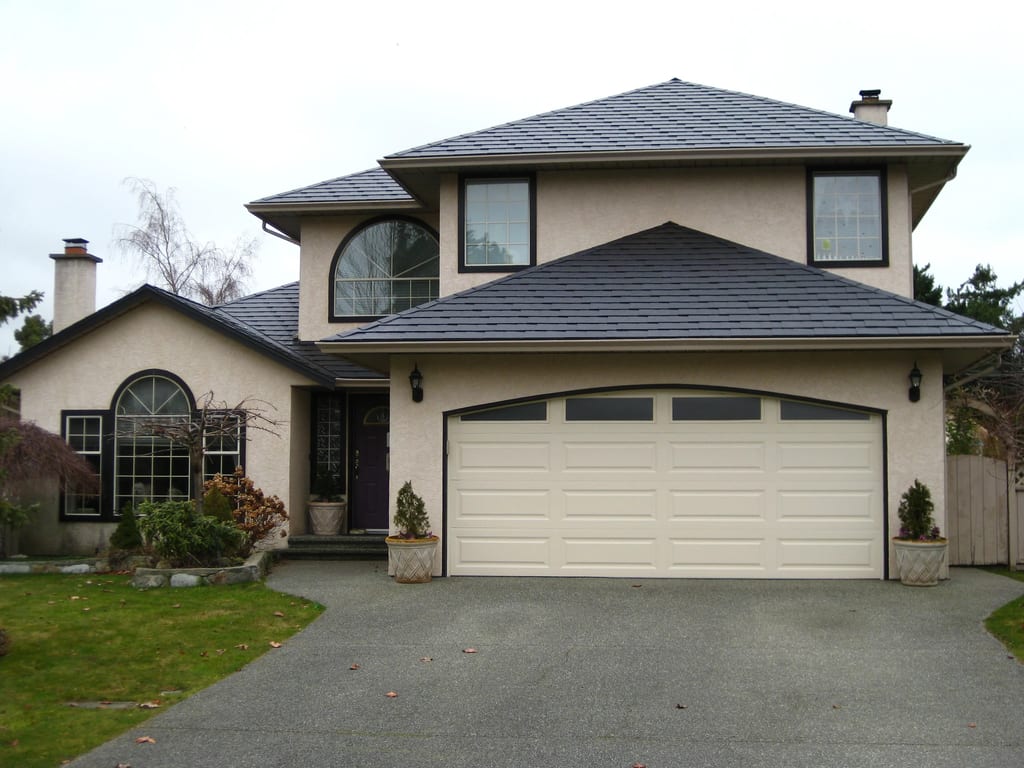 Black Interlock Slate aluminum roof on a beige two-storey home with dormers in a suburban setting, Victoria, British Columbia