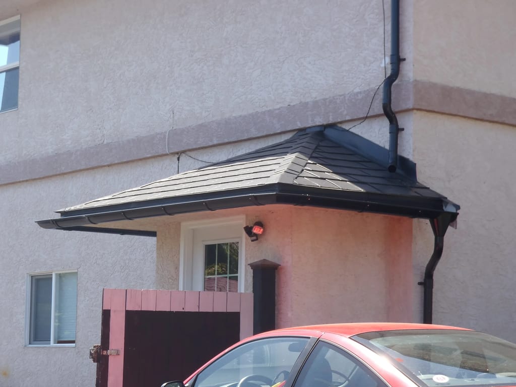 Black Interlock Slate aluminum roof on a pink house with a metal roof and a red car in front, Victoria, British Columbia