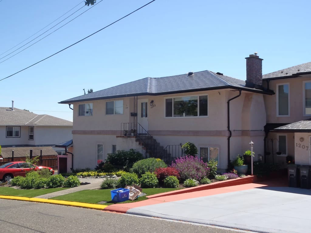 Black Interlock Slate aluminum roof on a beige two-storey home with a metal roof and chimney in a, Victoria, British Columbia