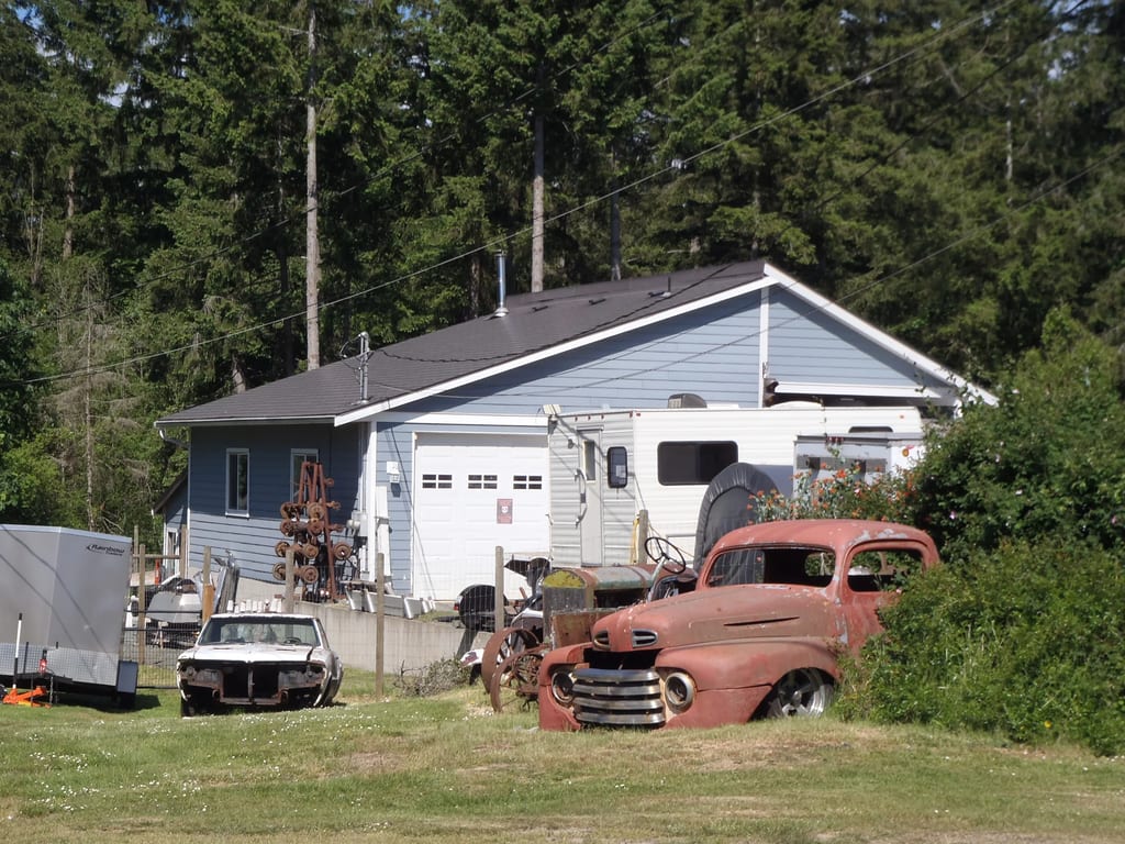 Weathered Interlock Slate aluminum roof on a blue single-family home with a garage in a forest clearing, Duncan, British Columbia