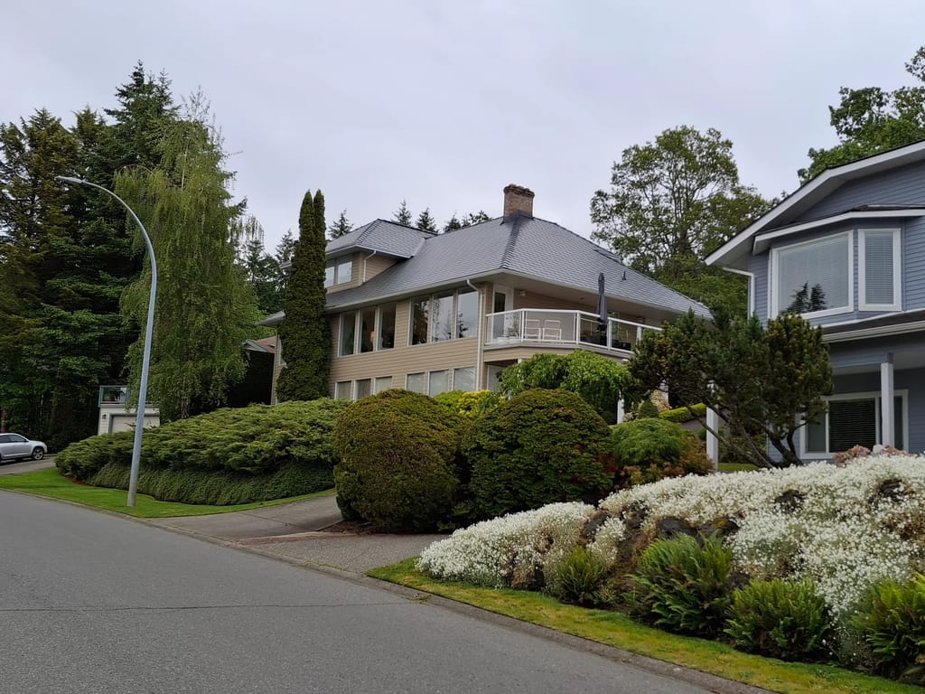 Deep Charcoal Interlock Slate aluminum roof on a modern home with a metal roof among tall trees, Duncan, British Columbia
