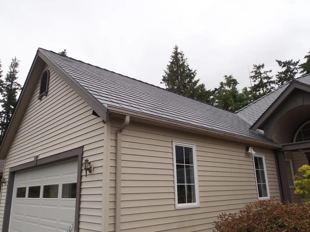Deep Charcoal Interlock Slate aluminum roof on a tan single-family home with a gable roof among coastal, Qualicum Beach, British Columbia