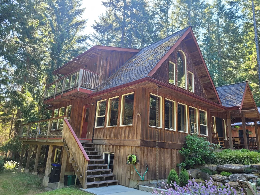 Deep Charcoal Interlock Slate aluminum roof on a brown chalet with a metal roof in a forested lakeside, Gabriola Island, British Columbia