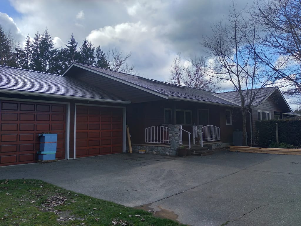 Tudor Brown Interlock Slate aluminum roof being installed on a Tudor brown metal roof on a ranch style house in a, Duncan, British Columbia