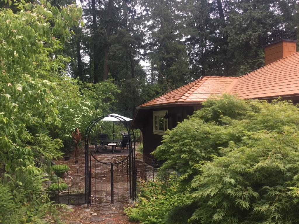 Copper Penny Interlock Slate aluminum roof on a brown home with a copper penny metal roof among tall, Cowichan Bay, British Columbia