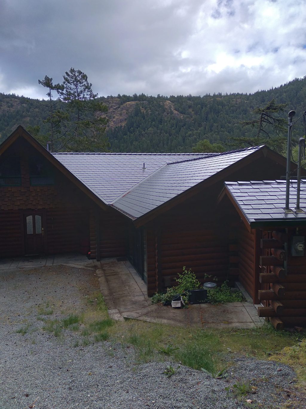 Deep Charcoal Interlock Slate aluminum roof on a dark wood chalet in the forest with a metal roof, Juan de Fuca, British Columbia