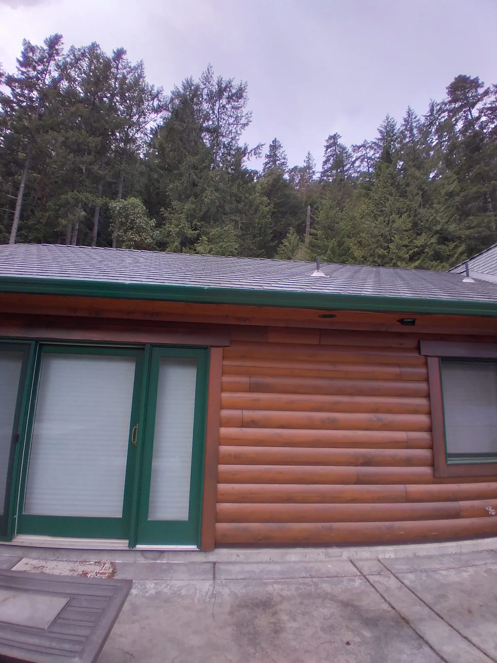 Deep Charcoal Interlock Slate aluminum roof on a log home with a metal roof in a forested rural setting, Juan de Fuca, British Columbia