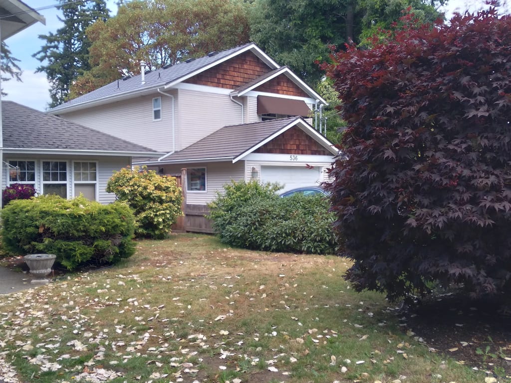 Tudor Brown Interlock Cedar Shingle aluminum roof on a Tudor style home with a metal roof surrounded by trees, Victoria, British Columbia